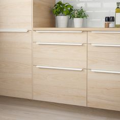 a kitchen with wooden cabinets and white counter tops, plants in pots on the counters