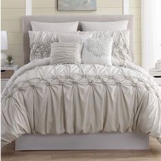 a bed with white comforter and pillows on it in front of a painting hanging above the headboard