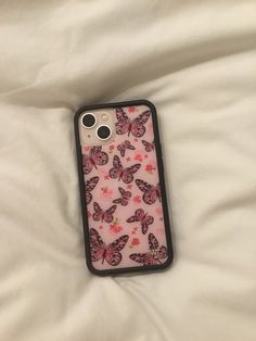 an iphone case with pink butterflies on it sitting on a white bed sheet in front of the camera