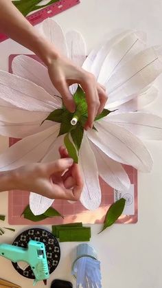 two hands are working on some paper flowers