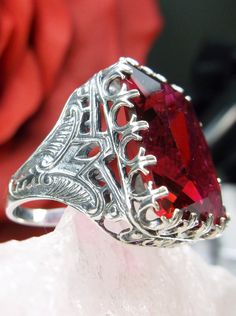 Simulated Red Ruby Ring Cardinal Design#215 Custom Made I now offer this is a brand new Art Deco reproduction ring in solid sterling silver. The gorgeous filigree ring is set with a flawless huge 30ct Man-made/simulated Red Ruby gemstone. The high-quality rectangle cut simulated Red Ruby is 20mm in length by 15mm in width (5/8th inch by 11/16th inch). the ring sits 9mm off the finger. The inside of the band is marked 925 for sterling. Notice the beautiful swirl like the craftsmanship of the silv Red Band, Sterling Silver Filigree, Cz Ring, Ruby Gemstone, Antique Design, Filigree Ring, Engraved Items, Ruby Ring, Silver Filigree