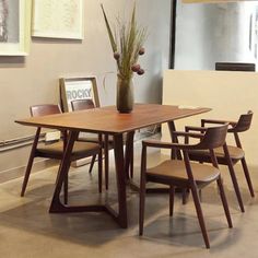 a wooden table with four chairs and a vase filled with flowers on top of it