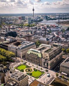 an aerial view of a city with lots of tall buildings and green grass in the middle