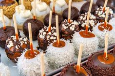 chocolate covered desserts are lined up on a tray with toothpicks sticking out of them