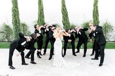 a group of people standing around each other in front of some trees and bushes with their hands together