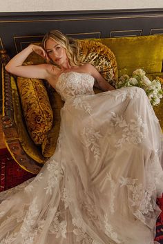 a woman in a wedding dress sitting on a couch with her hand on her head