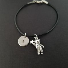 "Personalized Waxed Cord Bracelet! An astronaut charm on a black waxed cord makes the perfect gift for your loved one. The detailed astronaut bracelet charm is made from zinc alloy and measures 15 x 22 mm. The charm is not reversible. The bracelet is a waxed braided rope and measures 7.25\" with a 1-2\" extender. The lobster clasp is zinc alloy. The black cord bracelet can be personalized with a .5\" silver plated disc stamped with the initial of your choice. Each personalized bracelet arrives i Celestial Bracelet, Bracelet Cord, Moon Bracelet, Black Bracelet, Personalized Bracelet, Braided Rope, Cord Bracelet, Black Bracelets, Bracelet Charm