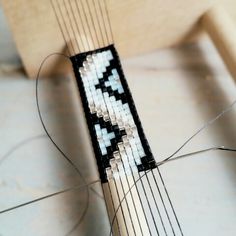 a close up of a piece of beaded material on a wooden board with strings