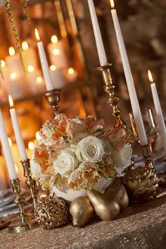 an arrangement of flowers and candles on a table