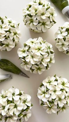 white flowers are arranged on a table with scissors and greenery next to the flowers