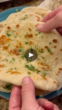 two hands reaching for an uncooked tortilla on a blue plate