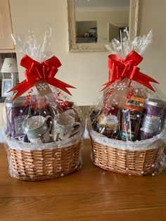 two wicker baskets with red bows and coffee mugs in them on a table