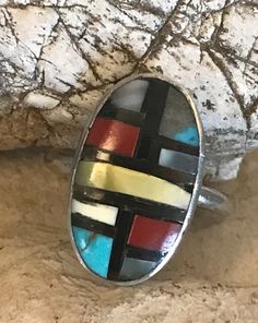 Vintage sterling Zuni ring with stone to stone inlay of coral, turquoise, shell, and onyx. There are slight gaps in places in the inlay. The ring is interesting, and I believe old. The artisan has chosen to include more gray matrix than turquoise in one panel. This is a soulful and colorful little artisan made ring. The ring is size 6-1/4. The face of the ring is .75 inches long and .47 inches wide. It weighs 3 grams. Artisan Oval Multi-stone Turquoise Ring, Handmade Artisan Multicolor Turquoise Ring, Handmade Multicolor Artisan Turquoise Ring, Unique Multicolor Cabochon Turquoise Ring, Unique Multicolor Turquoise Cabochon Ring, Multicolor Inlay Ring Jewelry, Multicolor Inlaid Ring Jewelry, Multicolor Bohemian Turquoise Ring With Inlay, Handmade Multicolor Southwestern Turquoise Ring