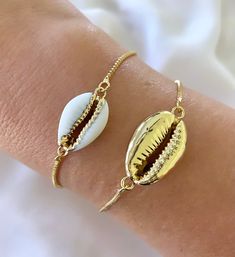 Features genuine Cowrie Shells, dipped in gold plating and affixed to a 14k gold filled box style chain. The bracelet is fully adjustable for a customized fit. Simply slide the gripper disc to your liking. It holds securely. Choose from White with gold trim or All gold. (Bamboo Cuff bracelet shown layered is available separately in the shop) Makes a great gift! I have Cowrie Necklaces available in the shop as well, so take a look around! *Please avoid showering, swimming or spraying perfume with Tarnish Resistant Gold Jewelry For Beach, Tarnish Resistant Gold Beach Jewelry, Dainty Resizable Jewelry For Beach, Adjustable Gold Plated Jewelry For Gift, Adjustable Gold-plated Jewelry For Gifts, Dainty Gold Bracelets For Beach, Dainty Gold Beach Bracelets, Dainty Gold Bracelet For Beach, Resizable Gold Jewelry As A Gift