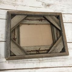 a wooden frame with barbed wire around it on a white painted wood wall, hanging from the ceiling