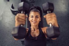 a woman is holding two dumbs in her hands and smiling at the camera,