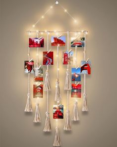 a wall hanging with pictures and string lights on it's sides that have tassels attached to them