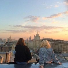 two women sitting on top of a building looking at the sky