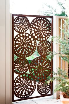 an iron screen on the side of a building with potted plants in front of it