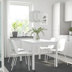 a white table and chairs in a small room with a potted plant on the window sill