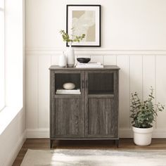 a wooden cabinet sitting next to a potted plant on top of a white rug