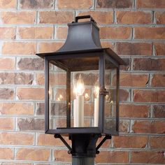 an old fashioned lantern with three lit candles in front of a brick wall