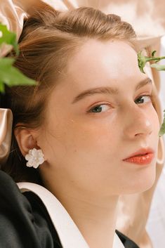 a woman with flowers in her hair wearing a black and white dress, looking off into the distance