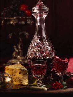 a glass decanter with some wine and cheese