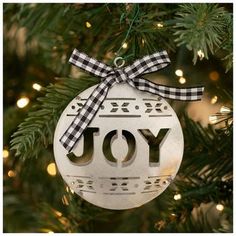 a white ornament hanging from a christmas tree with the word joy on it