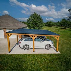 a white car parked under a covered carport in front of a house with a blue roof