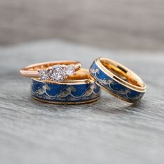 two gold and blue wedding rings with diamonds on them sitting on top of each other