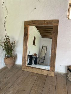 a mirror sitting on top of a wooden floor next to a potted plant