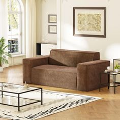 a living room with a couch, coffee table and rug on the hardwood flooring