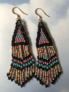 Stunning long metallic handmade seed earrings made with matte black square beads with pink, turquoise and soft matte pastel multicolored 11/0 seed beads. The earrings have long flowing fringe. The french hook earwires and findings are14kt gold plated. These gorgeous Cheyenne style earrings are super long and brush your shoulders ever so slightly. Great for daywear and stunningly beautiful for the night out. Earrings measure approximately 3-1/2 inches including ear wires. All items are handmade a Handmade Teardrop Bohemian Beads, Bohemian Teardrop Dangling Beads, Bohemian Adjustable Beaded Earrings With Large Beads, Festival Teardrop Beaded Fringe Jewelry, Festival Jewelry With Beaded Fringe, Southwestern Dangle Beaded Earrings For Festivals, Southwestern Style Dangle Beaded Earrings For Festivals, Southwestern Style Beaded Dangle Earrings For Festival, Festival Black Bead Drop Earrings