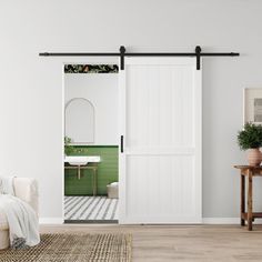 an open door leading to a bathroom with green tile flooring and white furniture in the background