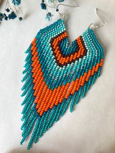 an orange and blue beaded necklace with matching earrings on top of a white table