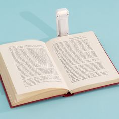 an open book with a white object sticking out of it's cover on a blue surface