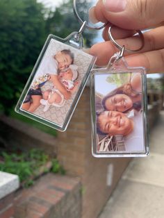 a person holding two key chains with pictures on them in front of a brick building