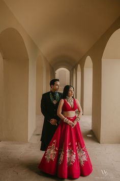 a man and woman in formal wear standing next to each other on a hallway way