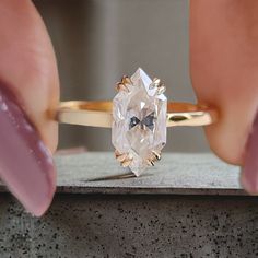 a woman's hand holding an engagement ring with a large diamond in the center