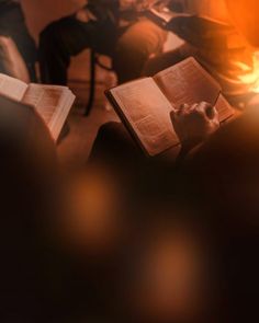 an open book sitting on top of a wooden table next to a fire burning in the fireplace