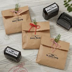 three brown paper bags tied with red and green twine on top of a white wooden table