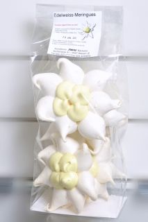 three white flowers sitting in a package on top of a table