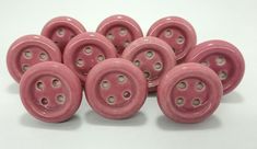 a pile of pink buttons sitting on top of a white table next to each other