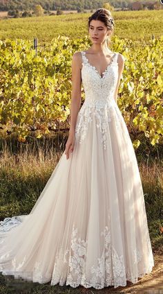 a woman standing in front of a vineyard wearing a wedding dress with flowers on it