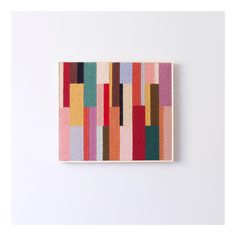 a colorful painting hanging on the wall next to a white wall with an orange, red, yellow and green stripe pattern