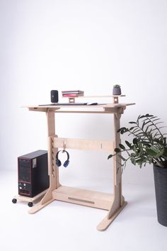 a computer desk sitting next to a potted plant on top of a white floor