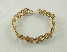 A stylish vintage Art Deco gold filled chain link bracelet, in yellow gold tone. The chunky links with entwined scrolls in love knot style, joined with an oval link. With a spring ring clasp. Marked for Kollmar & Jourdan, Pforzheim. Germany 1930s.  9.7g 19cm long.  In inches 7 3/8". Width 1cm.  In inches 3/8". FITTING A SMALL TO MEDIUM WRIST. In  good vintage condition with the gilding still intact. This item cannot be guaranteed nickel free. This item ships for free in a new gift box with track Victorian Gold Hallmarked Bracelet, Vintage Gold Link Bracelet Hallmarked, Vintage Yellow Gold Tarnish-resistant Bracelet, Luxury Vintage Gold-tone Bracelet, Vintage Gold-tone Brass Bracelet, Gold Filled Chain, Vintage Art Deco, Chain Link Bracelet, Link Bracelets