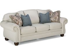 a white couch with blue and brown pillows on it's back cushions are in front of the sofa