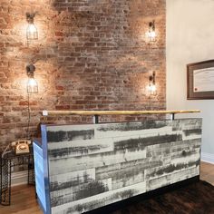 a brick wall behind a wooden counter in a room with wood flooring and exposed lighting